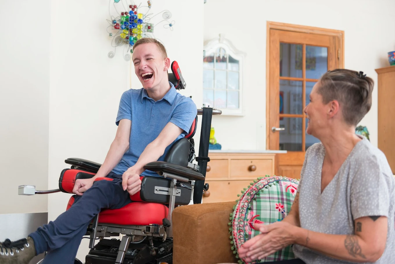 A senior woman and her caregiver laughing together, at ease and happy